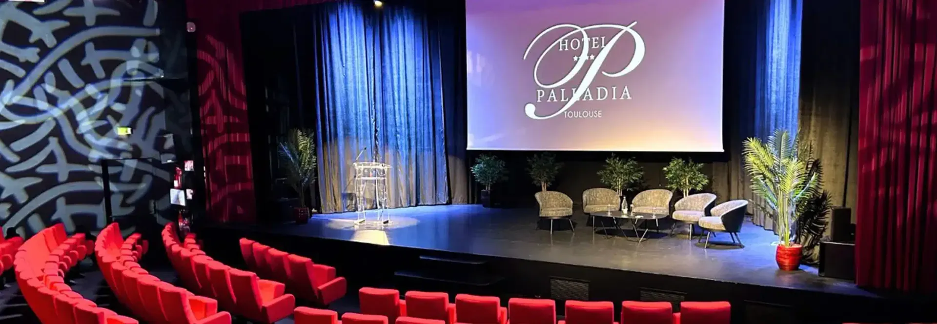 El auditorio del Hôtel Palladia: butacas rojas en grada frente al escenario