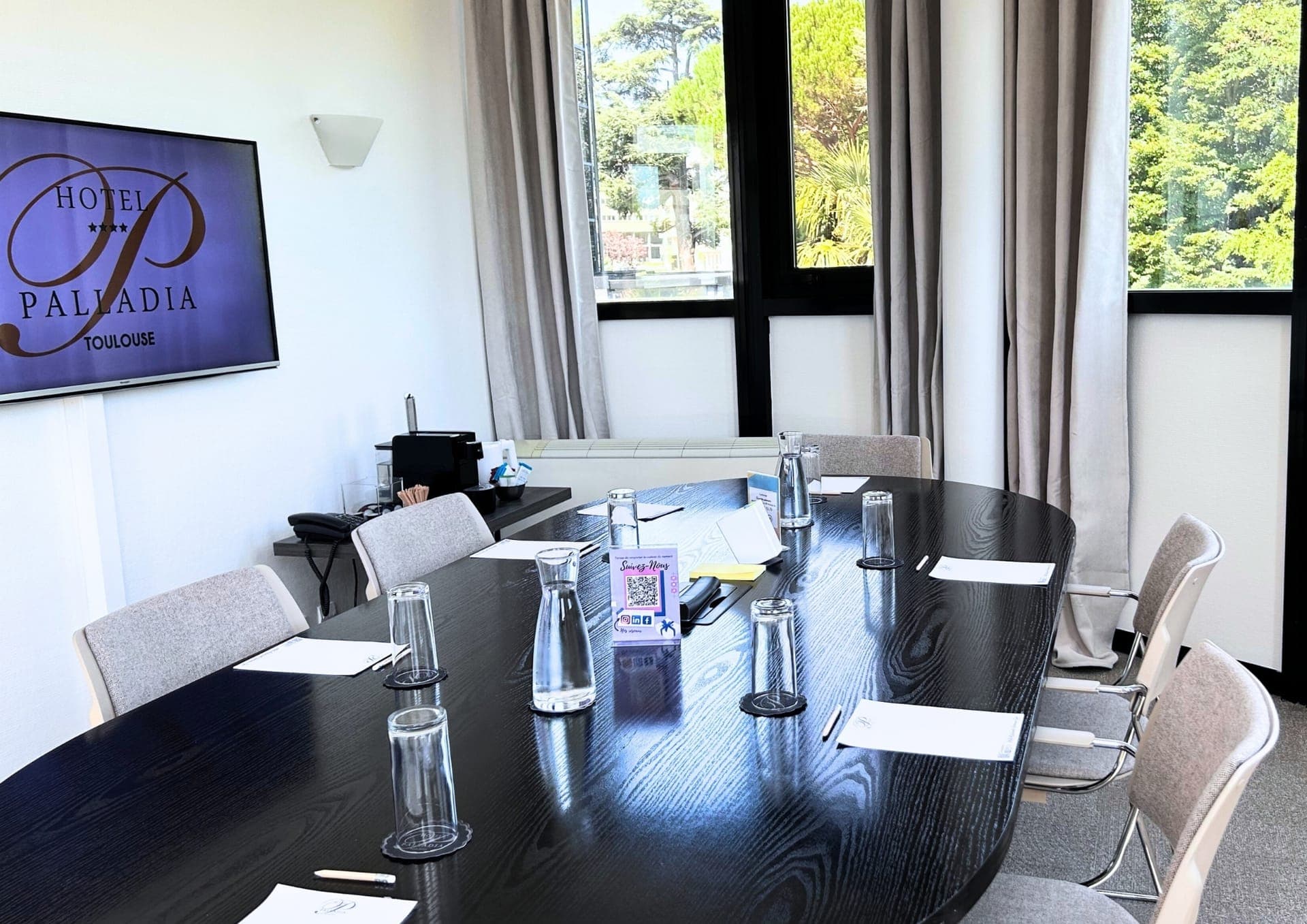 A meeting room at the Hôtel Palladia with an oval table and a view over greenery