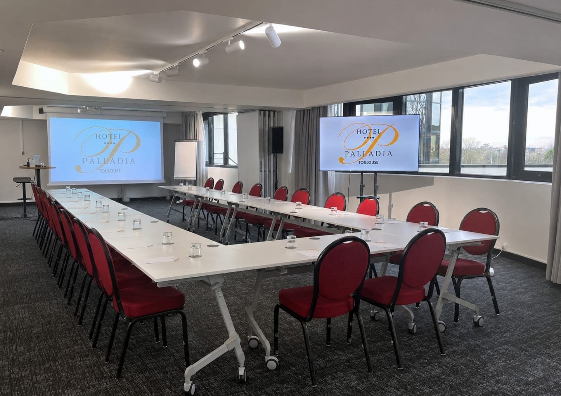 Sala de seminarios del Hôtel Palladia dispuesta en U, con dos pantallas